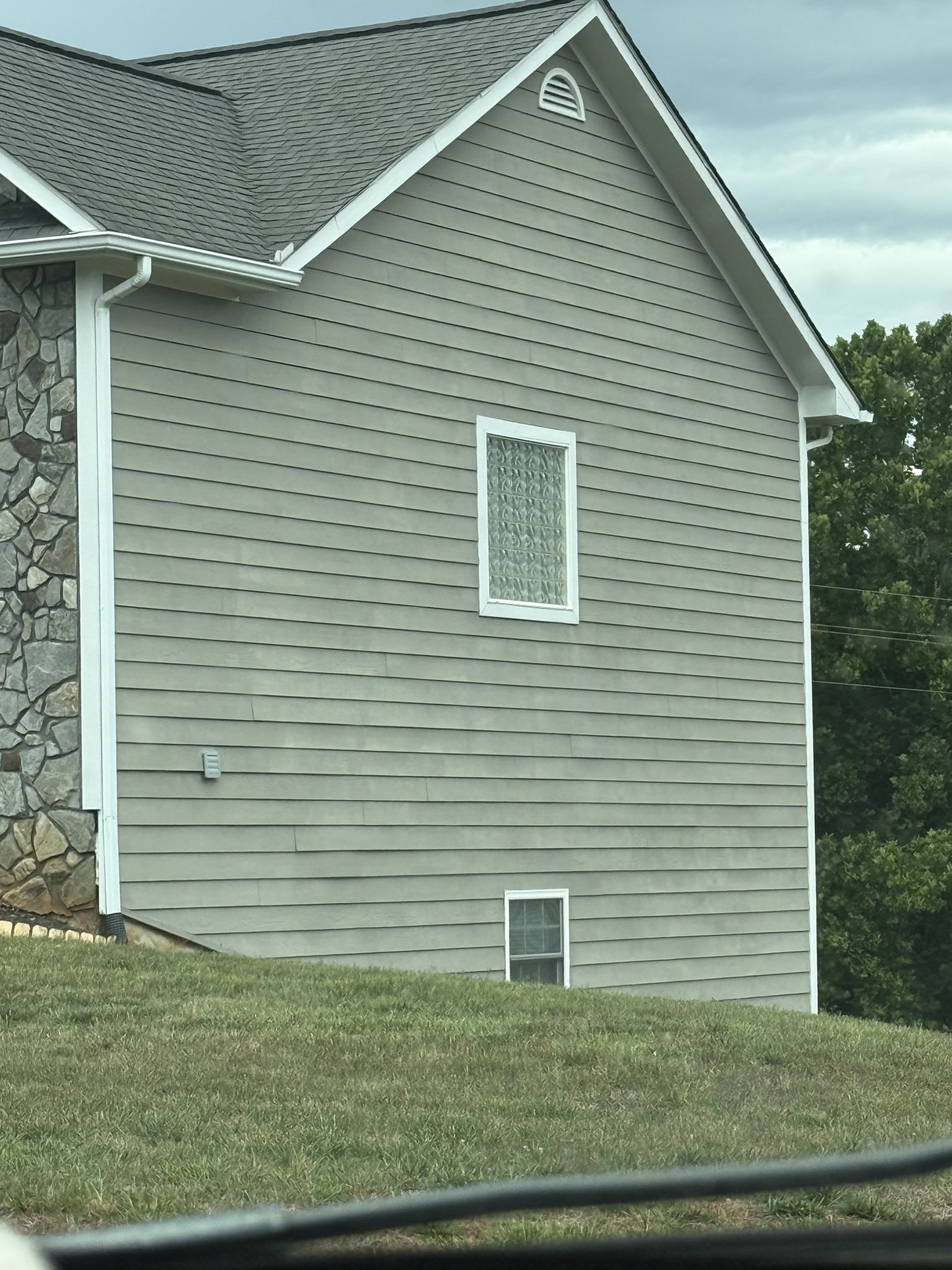 Uneven pressure washing streaks down the side of a home